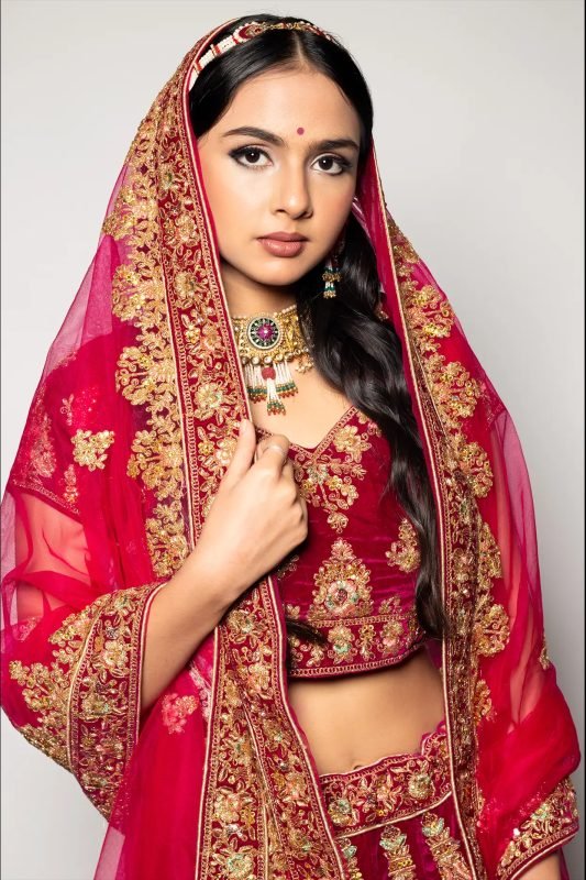 Bridal makeup: a red embroidered dupatta draped over the head, gold jewellery
